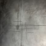 The artwork '888Hz' by Mathilde Lefort, viewed from an angle, showcasing its dark, burned and carved wooden frame. The frame, an integral part of the artwork, contrasts with the muted grey canvas and its minimalist iron line pattern. The carved patterns on the frame add a mystical dimension, suggesting an invitation to explore inner spirituality and the connection to earth elements.