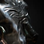 A close-up photograph of an aluminum sculpture's detailed surface, highlighting reflective qualities and textures. The metallic finish accentuates intricate details, showcasing dynamic interplays of light and shadow across the form
