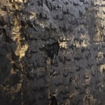 Close-up of Mathilde Lefort’s 'PROPHECY' showing the intricate texture and script-like elements. The canvas is dominated by black with corroded iron textures and interspersed with bright gold powder, creating an impression of ancient, weathered manuscripts. The gold appears as fragmented inscriptions or melodies, evoking a sense of timeless knowledge and mystical aura