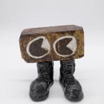 A sculpture by Kjelshus Collins of a clay brick with two eyes and a set of ceramic combat boots.