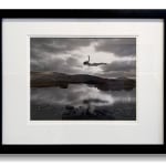 Silver gelatin print of Slate Gray Gallery artist Jerry Uelsmann's "Untitled, 1987 (Flying Figure Colorado) of a woman flying over a lake with mountains in the background in black and white