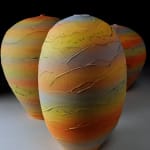 tall earthenware vessel with sunset bands of color with two other vessels in the background by potter Nicholas Bernard