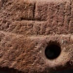 Ancient Red Stone Village Millstone on a wooden stand , most probably from Ghana.,