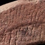 Ancient Red Stone Village Millstone on a wooden stand , most probably from Ghana.,