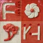 Ceramic sculpture of four blocks one with flowers and stems shaped like the letter F, one with a white flower, another with pink flowers and another with two sticks.