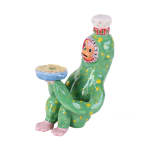 Ceramic sculpture of a monkey like creature sitting with his knees up towards his body, holding a quiche in a blue bowl. He has a small chef's hat on his head, he is green with yellow spots and has light pink hands and feet. His face is orange.