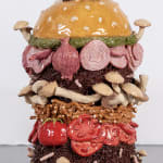 Lindsey Lou Howard sculpture of giant burger with onions, tomatoes, mushrooms, all in excessive amounts