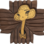 A piece of carved wood with a portrait in an illustrative style in gold leaf.