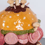 Detail of Lindsey Lou Howard sculpture of giant burger with onions, tomatoes, mushrooms, all in excessive amounts