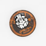 Circular metal tin with GATS character in black and white drawn on the top