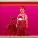 young boy painted in pink standing next to a bike