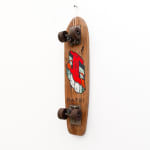 Brown wooden vintage skateboard with a slanted red face GATS character painted on the bottom of the board