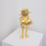 gold statue of a robot holding a heart on a white pedestal with white walls behind it