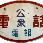 Back of the white, red, and black street sign with Japanese characters.