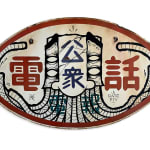 A street sign with Japanese characters and with artist's signature illustration of a masculine face with a long beard.