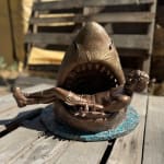 sculpture of a shark with a man in his mouth