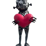 front view of a black and silver robot statue covered in designs holding a red heart