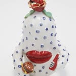 Ceramic figure of a white and blue spotted creature with giant red lips and a rose coming out of the top of its head. In its hands are a bottle of ketchup and a hamburger.