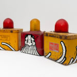 Two yellow with red light on top and a red with yellow light on top antique emergency road lights with GATS character painted across the three lights in black and white