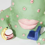 detail od Jen Dwyer sculpture of green cactus with pink lips holding laptop, banana and Nutella jar