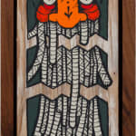 GATS character with long white tentacles and an orange and red face on a wood background