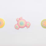 Installation shot of circular sculpture by Dan Lam with pink and purple circles and tiny bright yellow spikes
