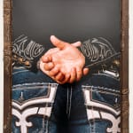 Photo of a persons back with embroidered jeans and black longsleeve shirt with their hands behind their back