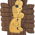 A piece of carved wood with an image of a woman in gold leaf painted in the center. She is holding 2 records.