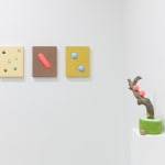 Install image of "Cosmic Bloom." From left to right, "Six Green Dots in Pale Peach," "Fluorescent Red Mound in Ash Rose," "Two Cool Spheres in Mustard," "Apple Elbow in Olive & Luminous Red."