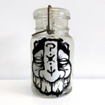 A glass jar with an abstracted masculine face decorated with details (symbols, patterns).