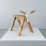 Brock DeBoer Sculpture of a porcelain bull head with gold horns on a wooden saw horse