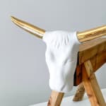 detail view of Brock DeBoer Sculpture of a porcelain bull head with gold horns on a wooden saw horse