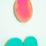 Detail view of Painting by Nick Schleicher comprised of elongated shaped panel with a separate circular panel above it. The circle is washed in fluorescent pink and orange paint and the lower panel is washed in fluorescent green and teal paint