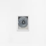 Ted Collier work on paper of vicious chaotic spiral in black in white charcoal framed in a white frame hanging on a white wall