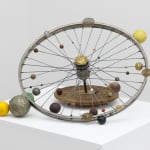 A bicycle wheel adorned with delicately carved orbs of varying sizes