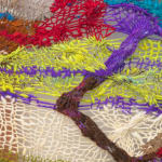 A close-up detail of a cacophonous composition in multi-colored fibers stretched across a redwood frame as one would stretch a painting. The fibers are knit at varying thicknesses so that in places one can see through the stitches to the wall behind. The composition has a wave-like pattern with many fractal fields of varying colors