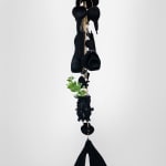 Black velvet flocked sculptures hanging from gold chains in a large room
