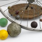 Detail of a bicycle wheel adorned with delicately carved orbs of varying sizes