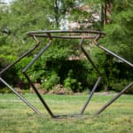 Outdoor installation view of a metal sculpture that resembles an angular vessel set in a green park at Socrates Sculpture Park