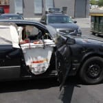 Still image from video showing car with an open door revealing a makeshift desk