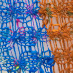 A detail of blue and orange knitting, allowing the viewer to see the varying weave