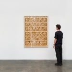 a laser sculpted wood sculpture on a white wall with a figure looking at it