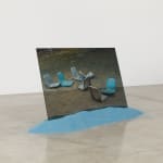 Karyn Olivier's (Dis)(Re)(In)place, a photographic print on translucent plastic of chair seats on the ground, planted in blue sand in a neutral gallery space