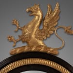 Regency carved giltwood and ebony convex mirror with griffin crest