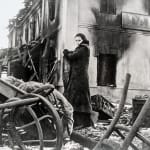 Black and white photograph of Geraldine Chaplin in a scene depicting the Soviet Union, a war torn landscape with charred buildings and rumble, on the set of “Doctor Zhivago”