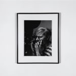 Framed Black and white photograph of Andy Warhol looking into a film camera and biting his nails