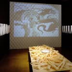Art installation, video projection with animation, table and walls covered with soap molds of dolls
