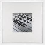 Framed Black and white photomontage of a three dimensional structure in the form of raised grid lines, viewed from above
