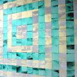 Detail of a sculpture composed of alternating green and beige iridescent concentric squares, each made up of smaller cubes