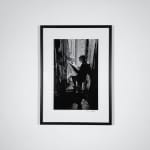 Framed Black and white photograph of Andy Warhol reading the newspaper next to an open door in a foil-lined room